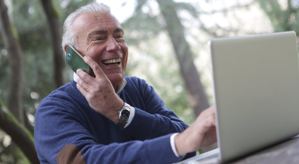 Older gentleman using phone and computer
